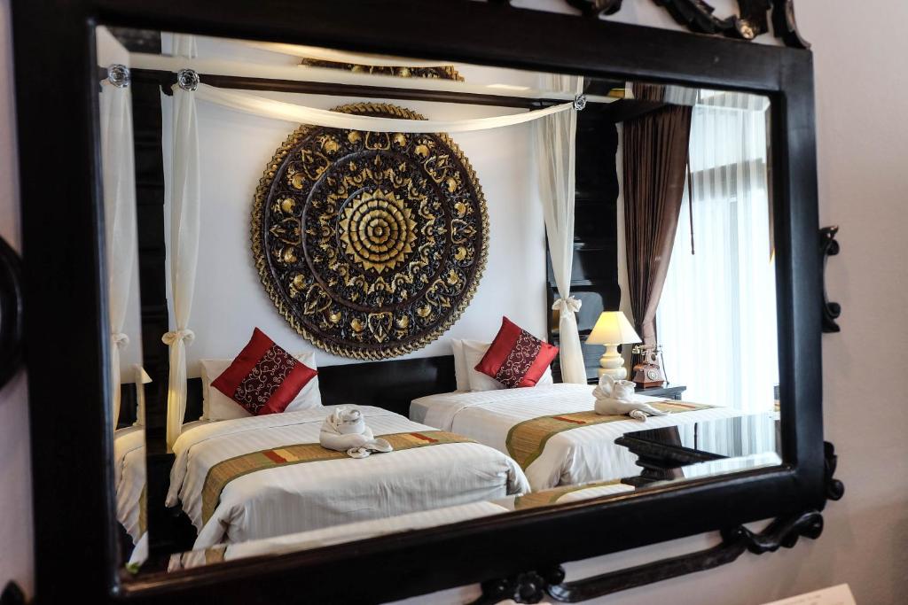 a mirror reflecting a bedroom with two beds and a headboard at Villa Sirilanna Hotel in Chiang Mai