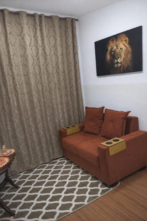 a living room with a couch with a lion on the wall at Flat Maya in Barretos