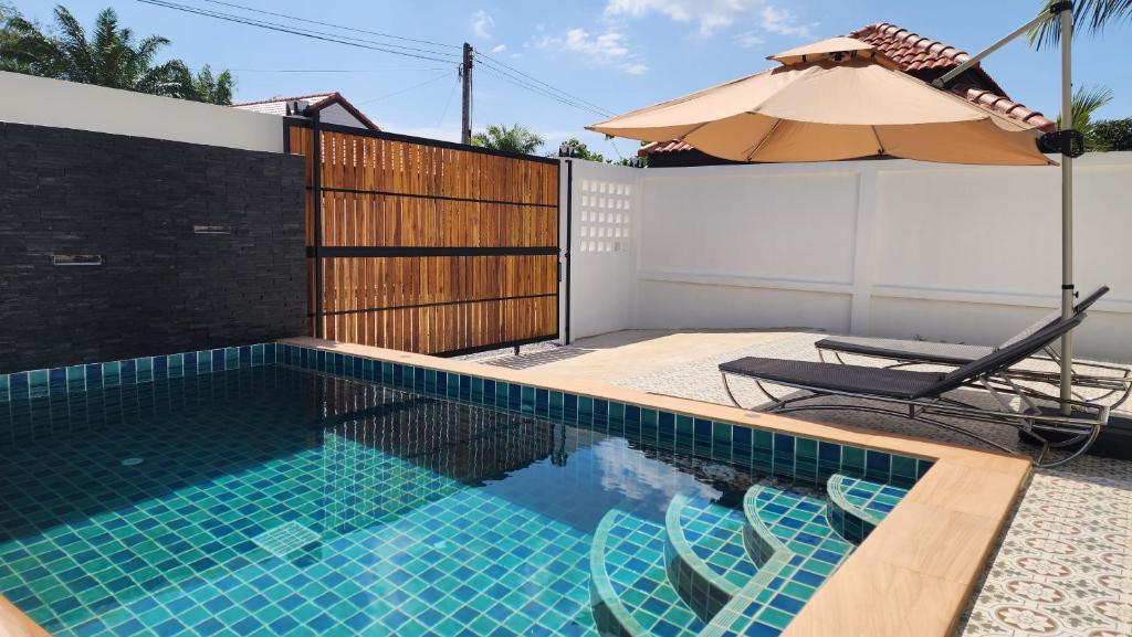 a swimming pool with two chairs and an umbrella at Pana Villa Koh Lanta in Ban Ai Dao