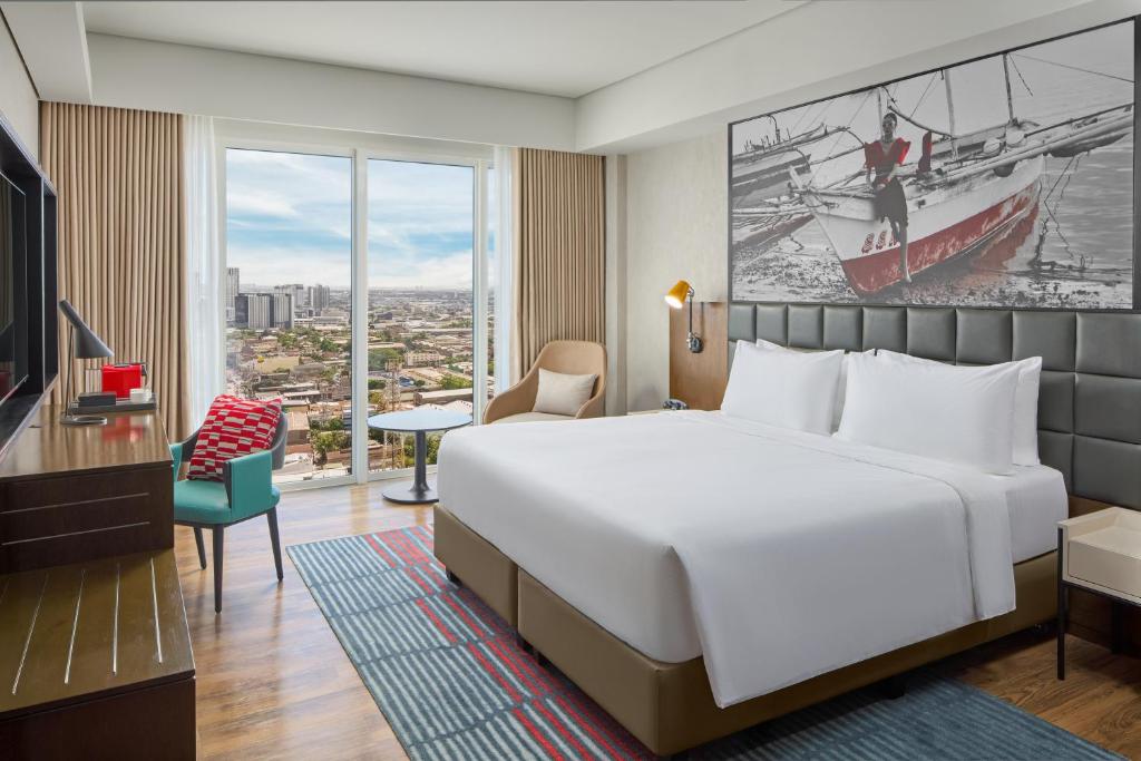 a hotel room with a large bed and a large window at Radisson RED Cebu Mandaue in Cebu City