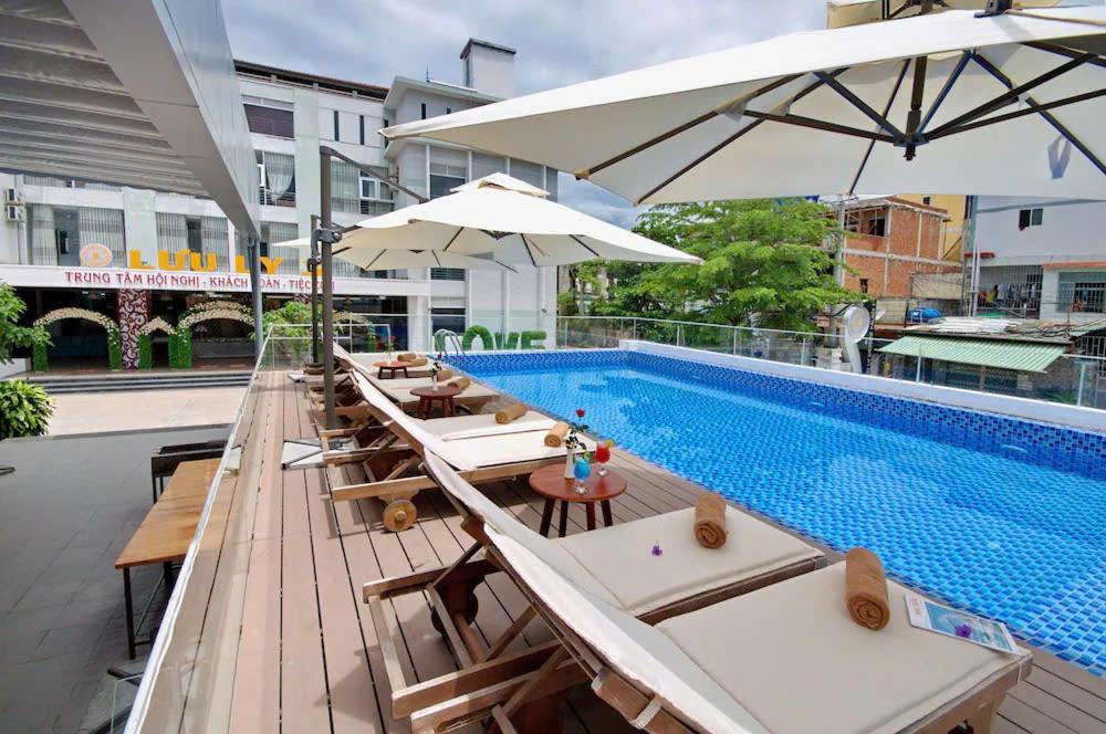 a row of chairs and umbrellas next to a swimming pool at Dolphin Bay Hotel Nha Trang in Nha Trang
