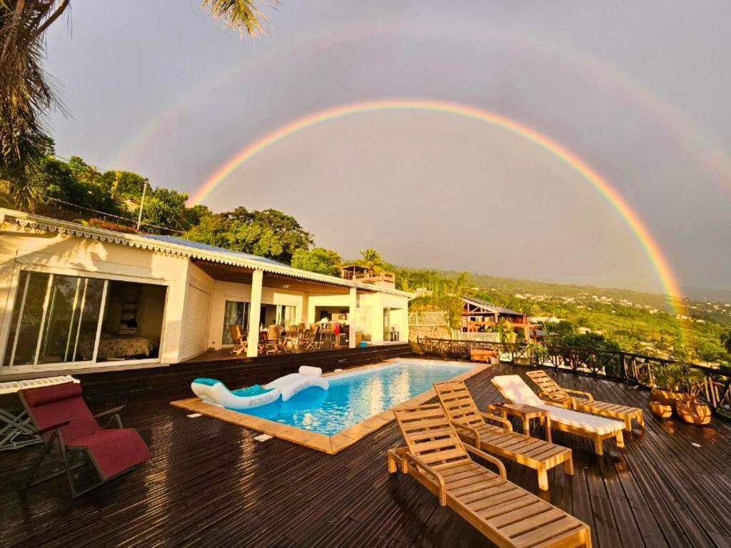 a rainbow over a house with a pool and a pool slide at Home Ocean 360 piscine chauffée et SPA in Saint-Leu