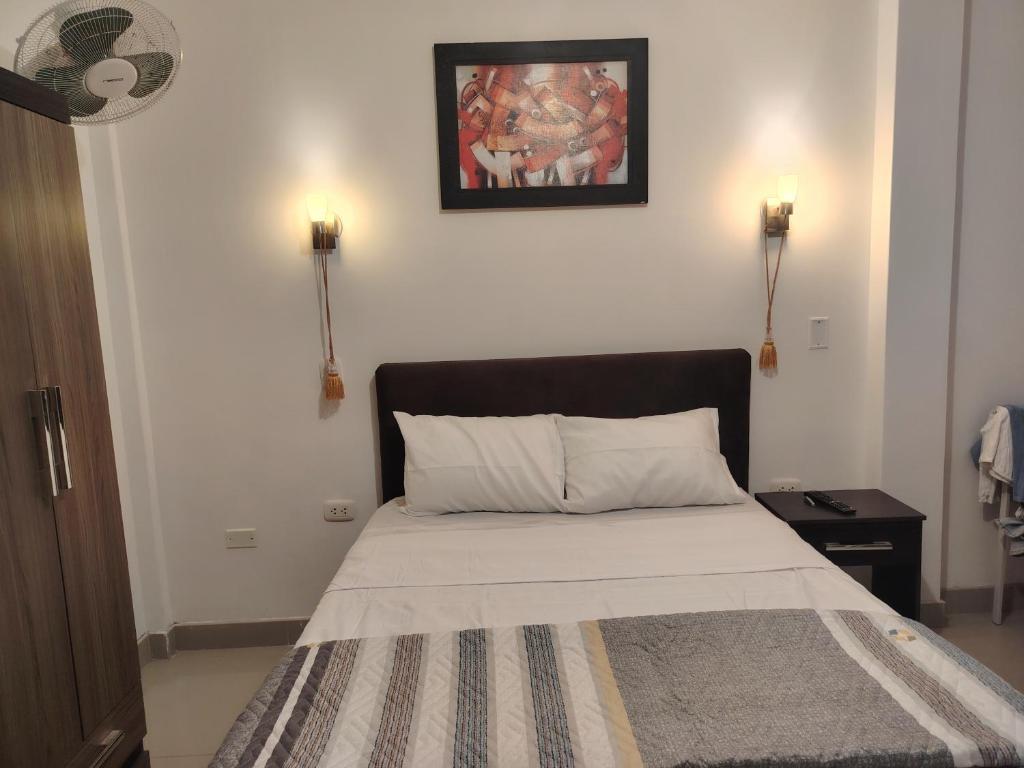 a bedroom with a bed with a picture on the wall at Hospedaje Kaiak in Pacasmayo