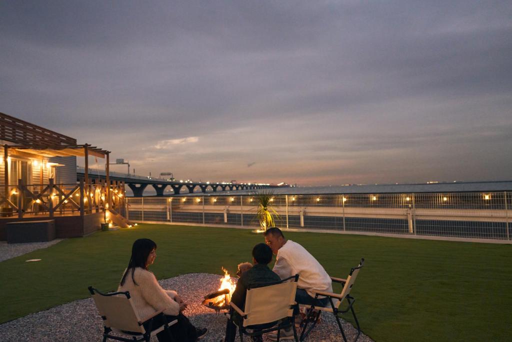 a group of people sitting around a fire at night at Solana木更津 in Kisarazu