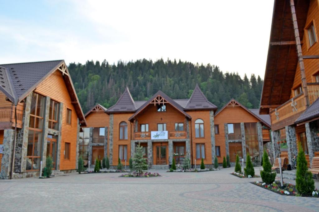 a row of wooden buildings with trees in the background at Sribni Rosy in Mykulychyn