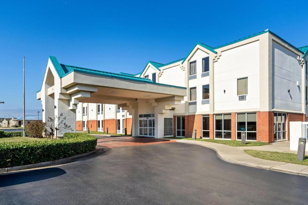 a large white building with a parking lot at Days Inn & Suites by Wyndham Ridgeland in Ridgeland