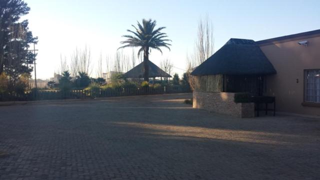 a parking lot with a building and a palm tree at Kleinplaas Guest Farm in Potchefstroom