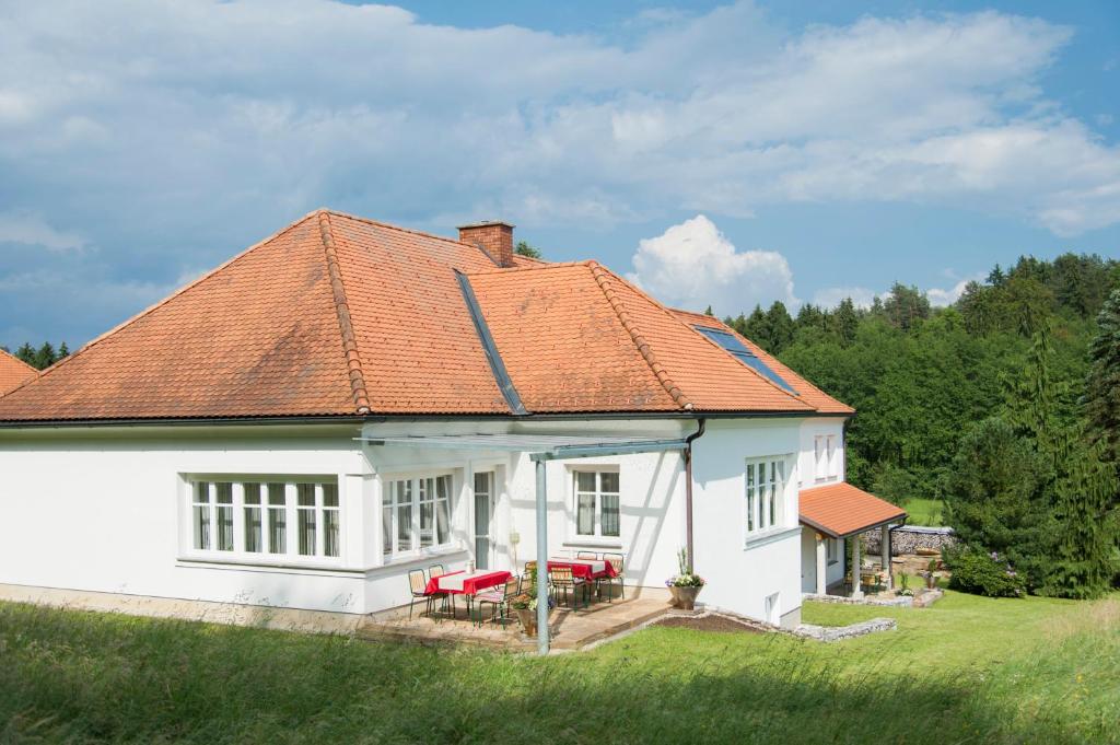 ein weißes Haus mit orangefarbenem Dach in der Unterkunft Haus Steirer am Kaiserwald in Premstätten