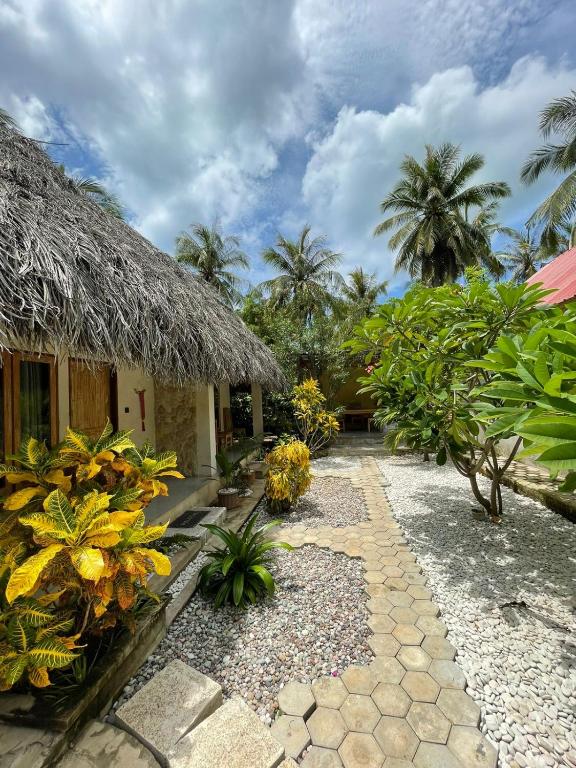 a house with a thatched roof and a pathway at Oemau Bungalow in Nembrala