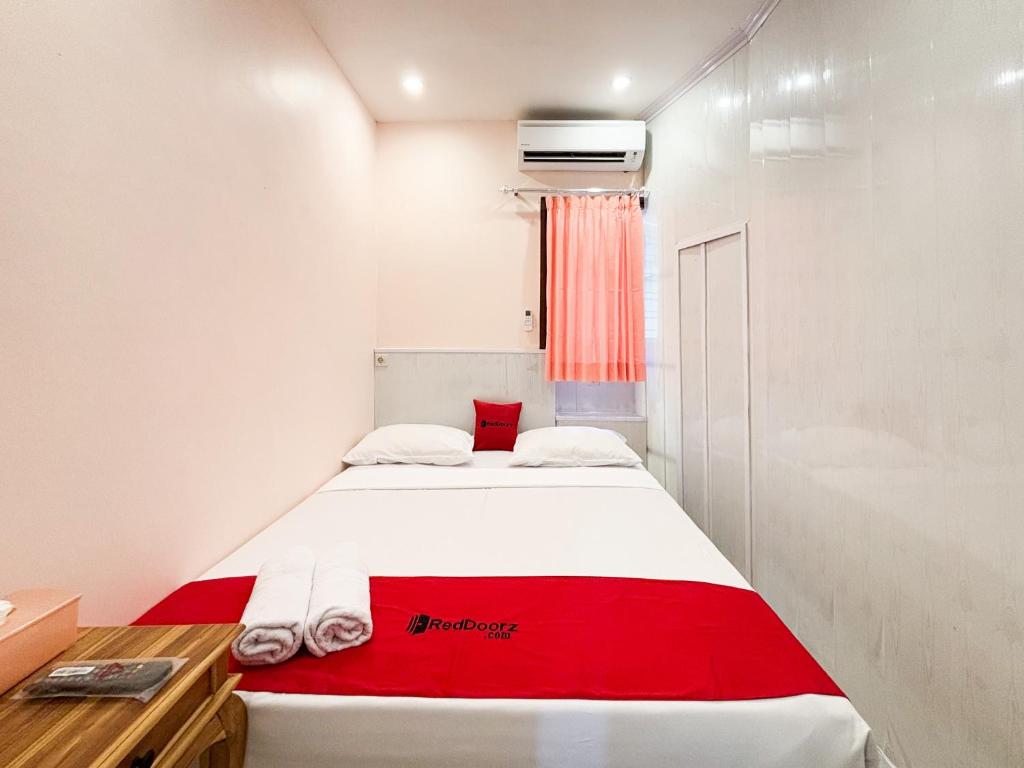 a bedroom with a bed with a red blanket at RedDoorz Plus near Brawijaya Museum in Malang