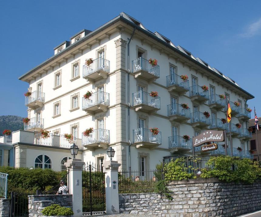 Un grand bâtiment blanc avec balcon se trouve dans une rue. dans l'établissement Hotel Lario, à Mezzegra