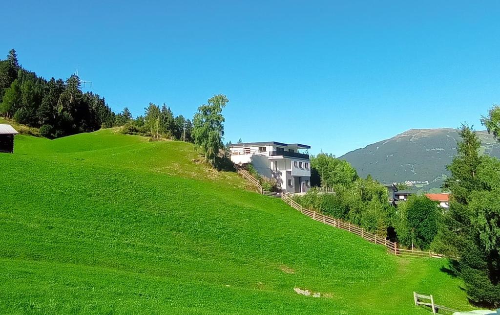 a green hill with a house on top of it at Panorama Wildgrat in Wenns