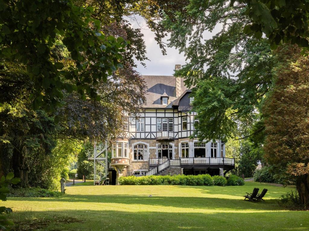 a large house on a lawn with trees at Beautiful castle in Spa wit garden in Spa