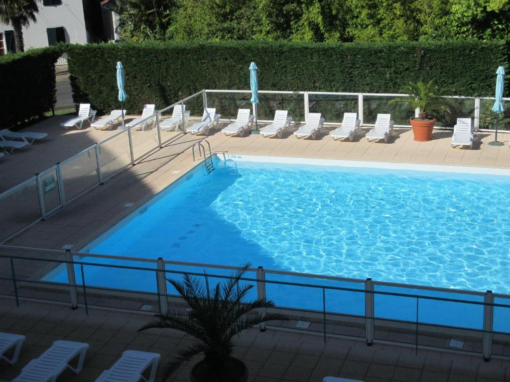 une grande piscine bleue avec des chaises longues dans l'établissement Appartement Golf et Nivelle avec piscine et parking, à Ciboure