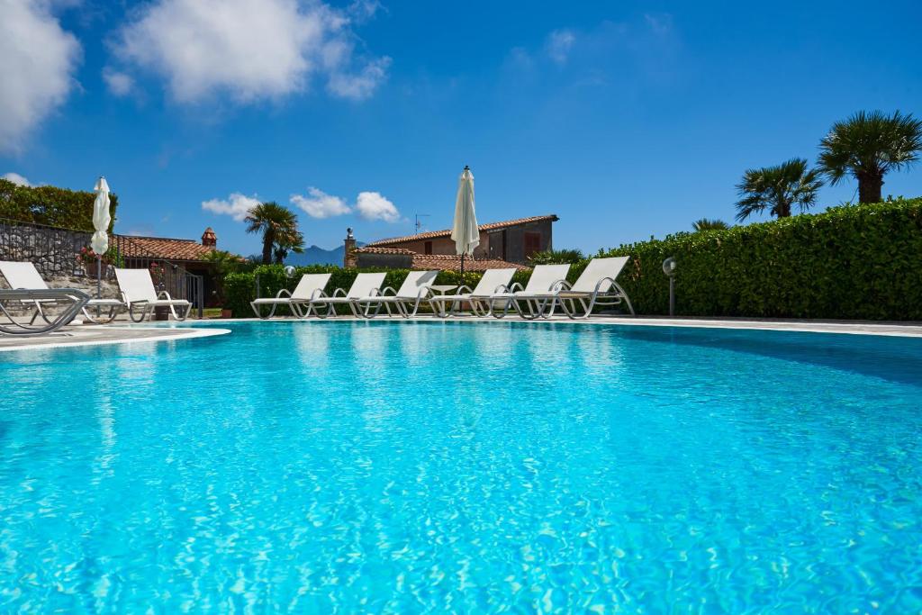 a large blue swimming pool with chairs and umbrellas at Villa Favara in Scala