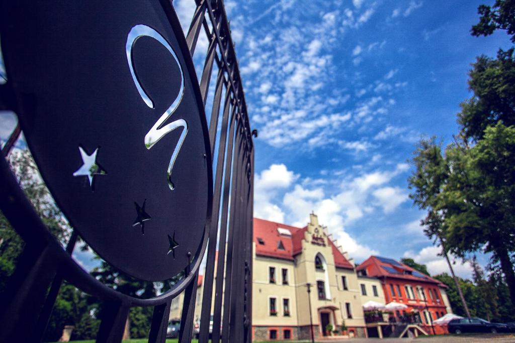 une clôture en fer avec un panneau devant un bâtiment dans l'établissement Hotel Niemcza Wino & Spa, à Niemcza