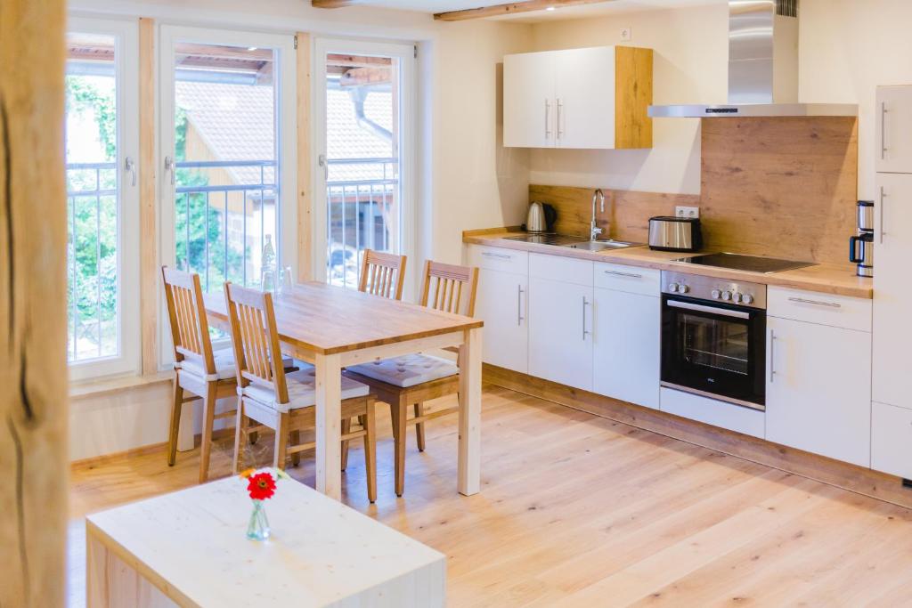 una cocina con armarios blancos y una mesa y sillas de madera. en Hellbachhof, en Equarhofen