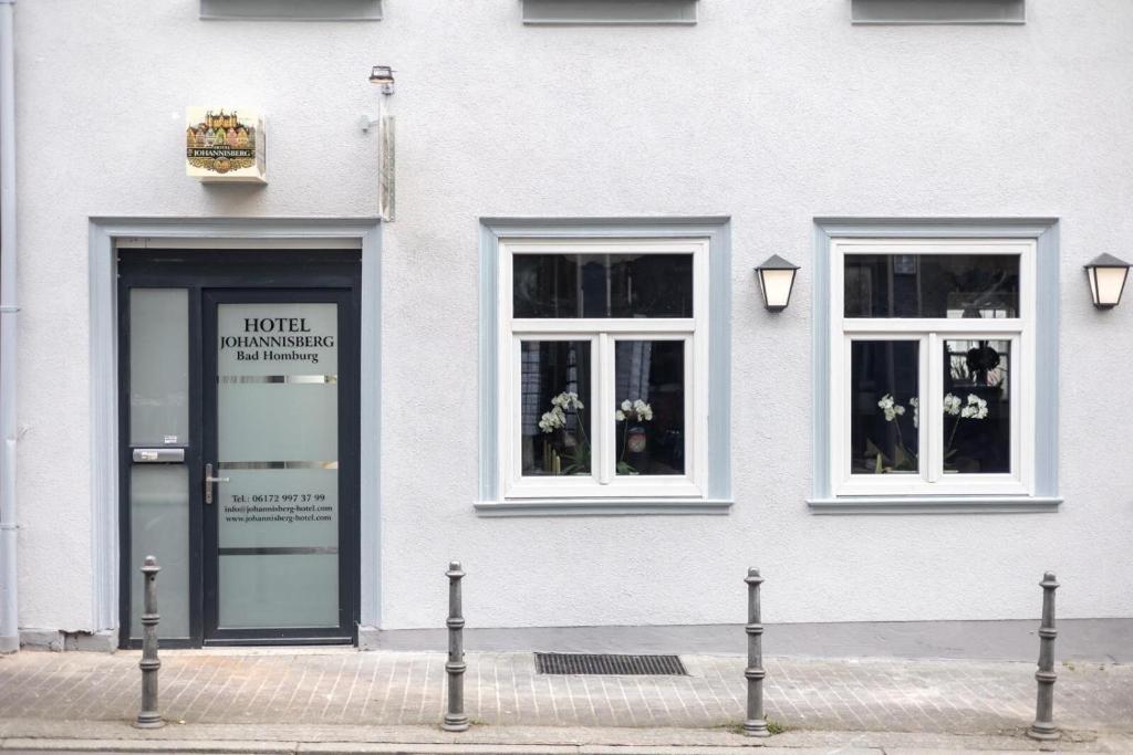 a white building with a door and two windows at Hotel Johannisberg Bad Homburg in Bad Homburg vor der Höhe