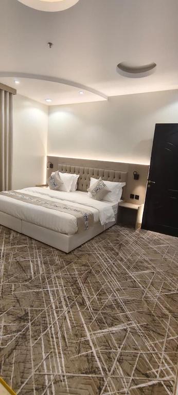 a bedroom with a large white bed with a carpet at عز الاصالة للشقق المخدومة تصنيف اقتصادي in Taif