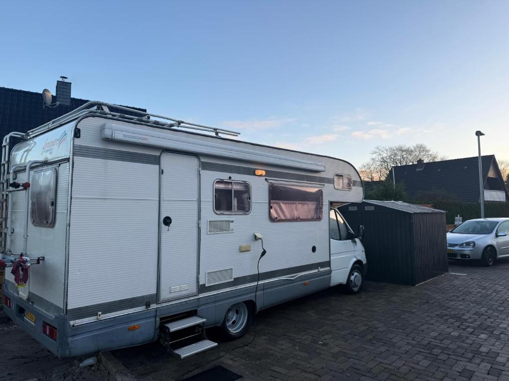 a silver trailer is parked in a parking lot at Camper room bunde in Bunde