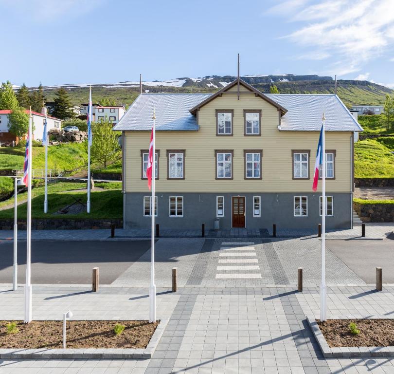 a large yellow building with flags in front of it at Fosshotel Eastfjords in Fáskrúðsfjörður
