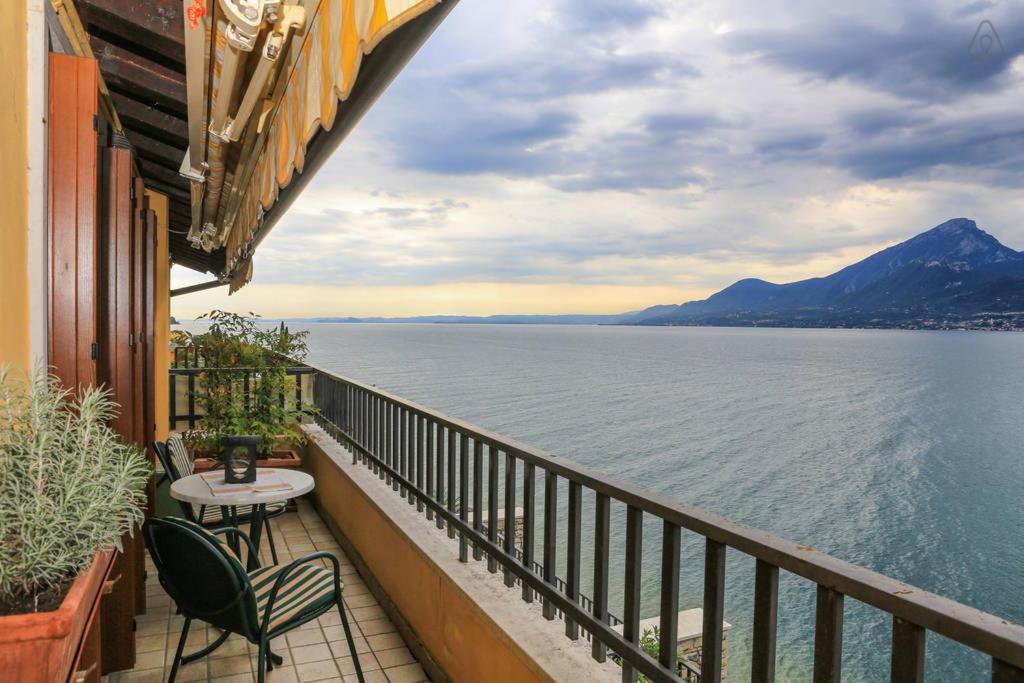 un balcone con tavolo e sedie accanto all'acqua di Holiday Home Thomas and Friends a Brenzone sul Garda