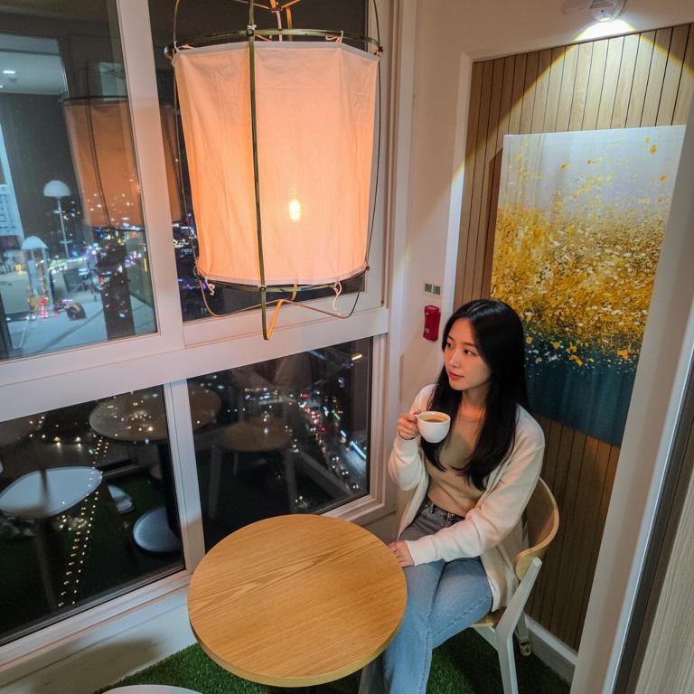 a woman sitting at a table drinking a cup of coffee at Icheon Hutis stay in Icheon