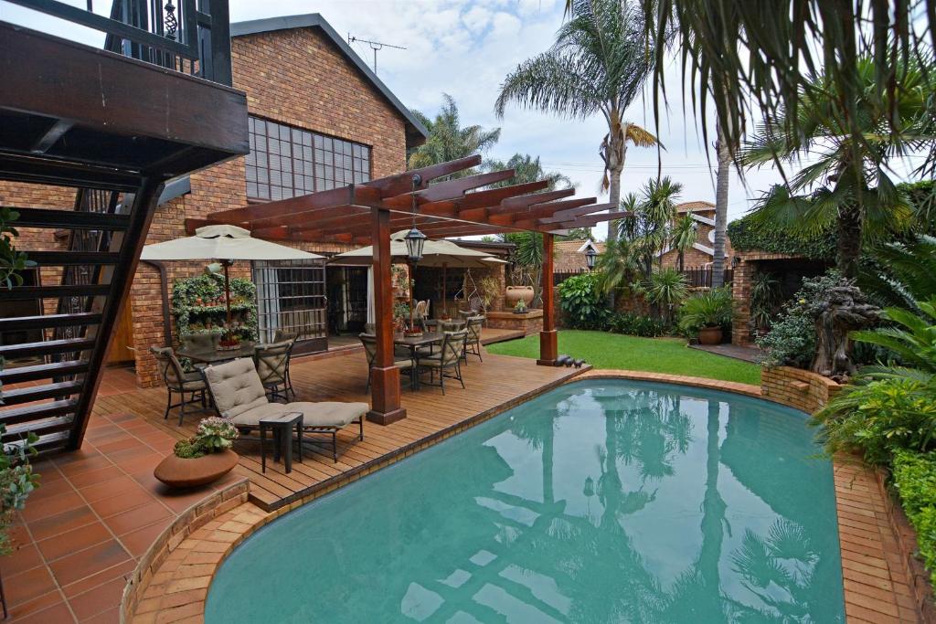 a swimming pool with a patio with tables and chairs at Africa House Guesthouse in Centurion