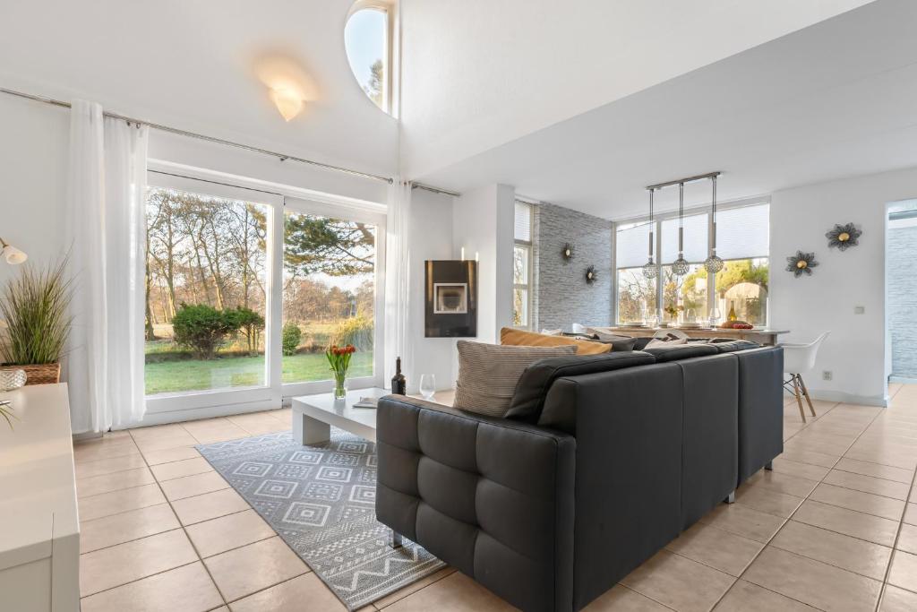 a living room with a black couch and some windows at Villa Beach & Golf in Julianadorp