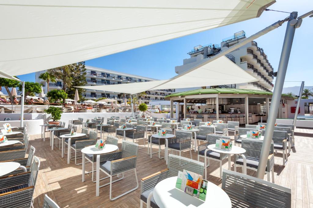 an outdoor restaurant with tables and chairs and white umbrellas at Tigotan Lovers & Friends Playa de las Americas - Adults Only (+18) in Playa de las Americas