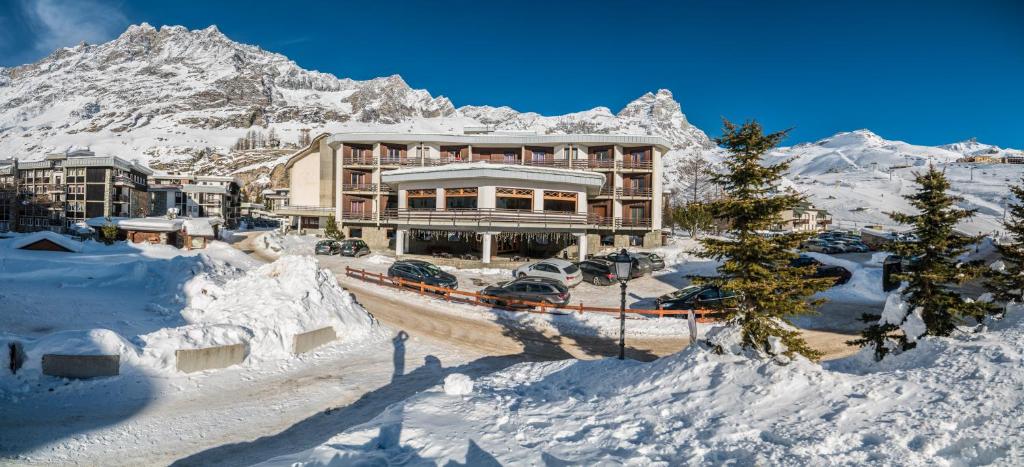 un bâtiment dans la neige devant une montagne dans l'établissement Hotel Europa, à Breuil-Cervinia