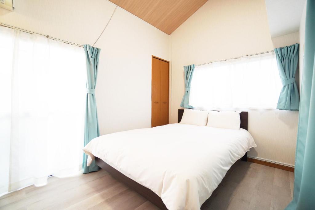 a bedroom with a bed and two windows at Mary's Room Sumiyoshi in Sumiyoshi