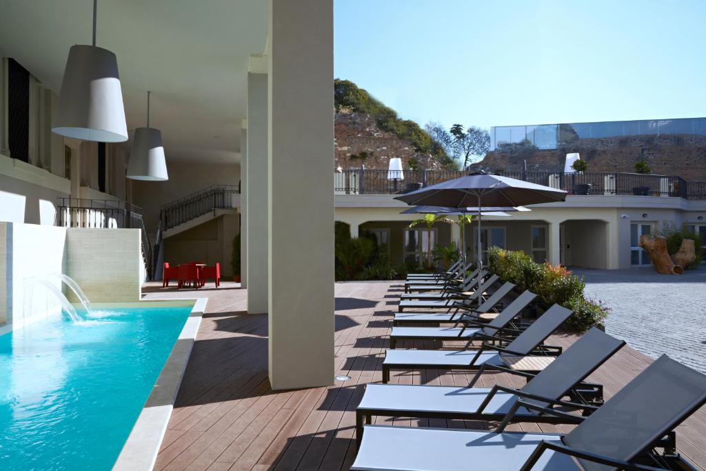 een rij ligstoelen en een zwembad met een parasol bij Hotel The Building in Rome