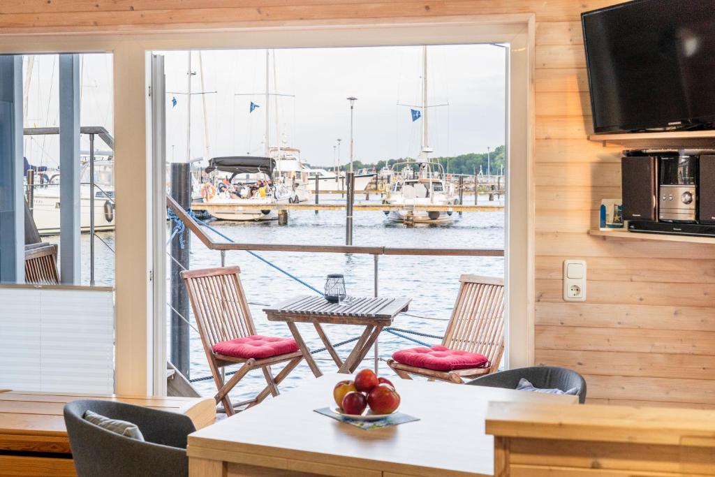 a room with a table and chairs and a view of the water at Hausboot Baltic Goose in Burgtiefe auf Fehmarn 