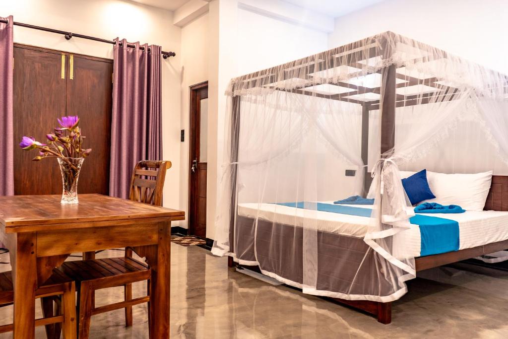 a bedroom with a canopy bed with a table and a desk at Villa Paddy Heaven in Unawatuna