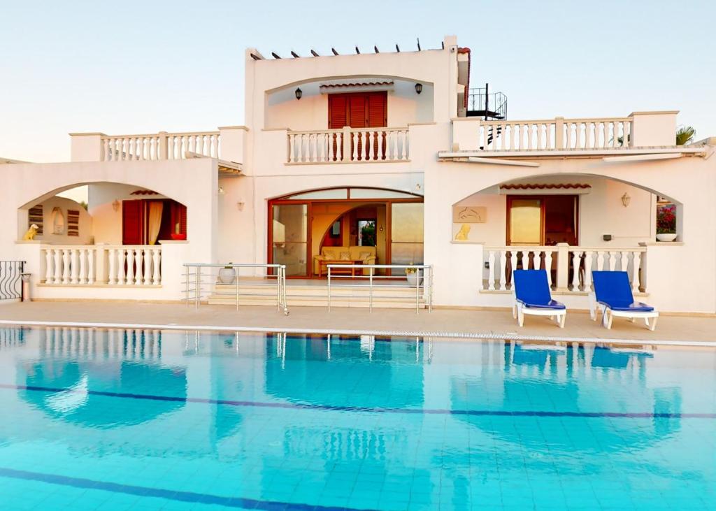 a house with a swimming pool and two blue chairs at Villa Magic Sunset in Kyrenia