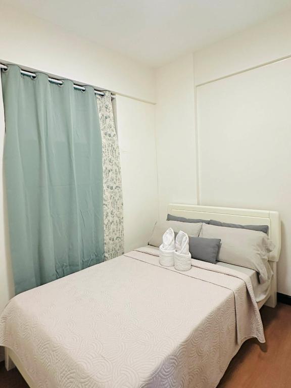 a white bed in a room with blue curtains at POOLVIEW 2 bedrooms unit in Davao City