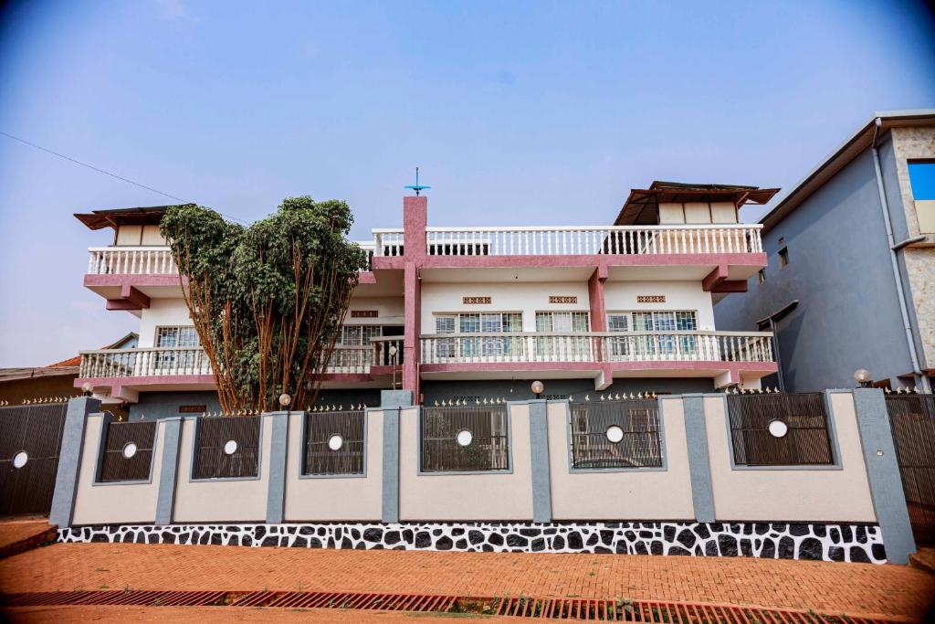 a pink and white building with a tree in front of it at Welcome Inn Guest house in Kigali