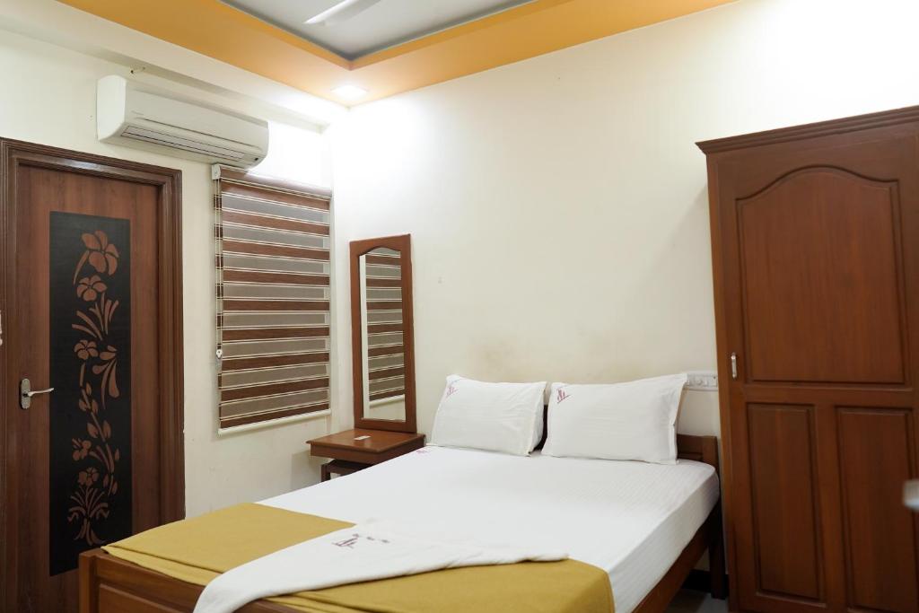 a bedroom with a white bed and a wooden cabinet at Thai Residency - Opp to Bus Stand in Dhārāpuram