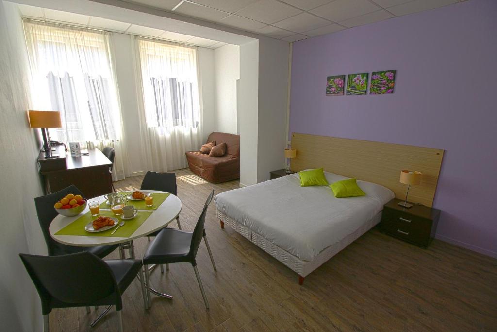 マコンにあるKOSY Appart'Hôtels - Le Cours Moreauのベッドルーム1室(ベッド1台、テーブル、椅子付)
