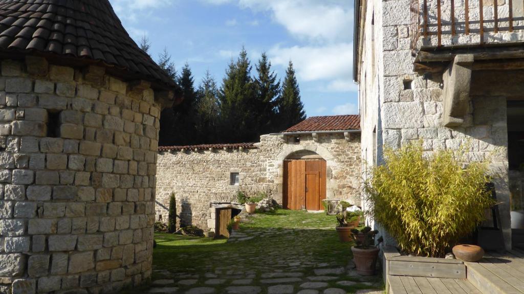 un edificio de piedra con una puerta de madera en un patio en La Fortance Paradis Naturel - Proche de la ville en Planfoy