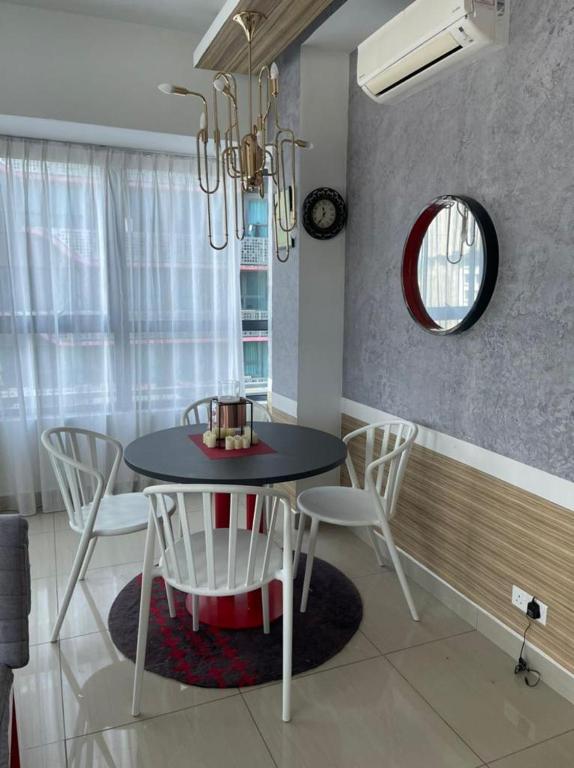 a dining room with a black table and white chairs at Arte Plus Homestay Condo in Kuala Lumpur