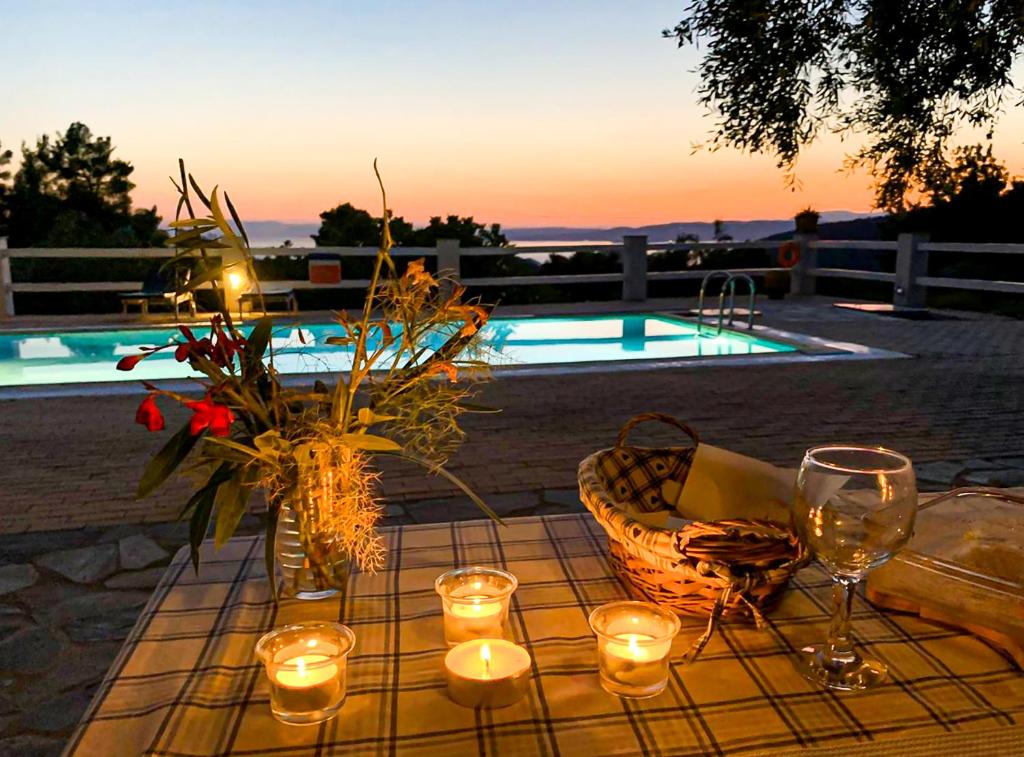 a table with candles and wine glasses next to a pool at Villa Jasmine - Peaceful Sunset View Retreat in Skopelos Town
