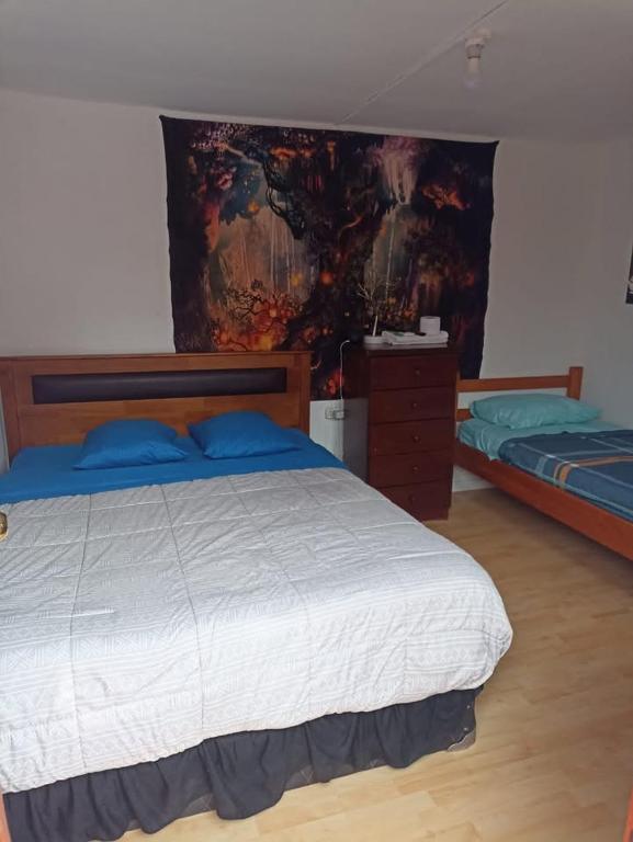 a bedroom with two beds and a painting on the wall at El valle in Copiapó