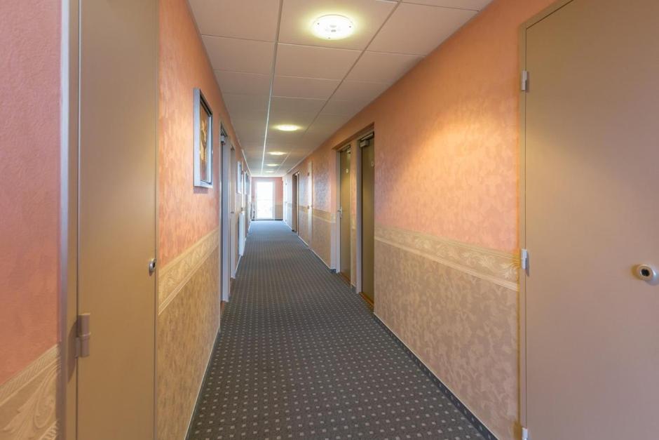 un pasillo de un edificio de oficinas con un pasillo largo en Pressoir Hôtel en Saint-Calais