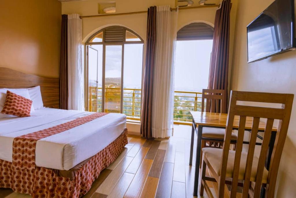 a bedroom with a bed and a table and a balcony at Hôtel Saint Jean Leopold in Kigali