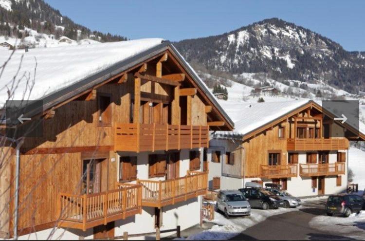 a large wooden building with cars parked in a parking lot at Chalet des Evettes in Flumet