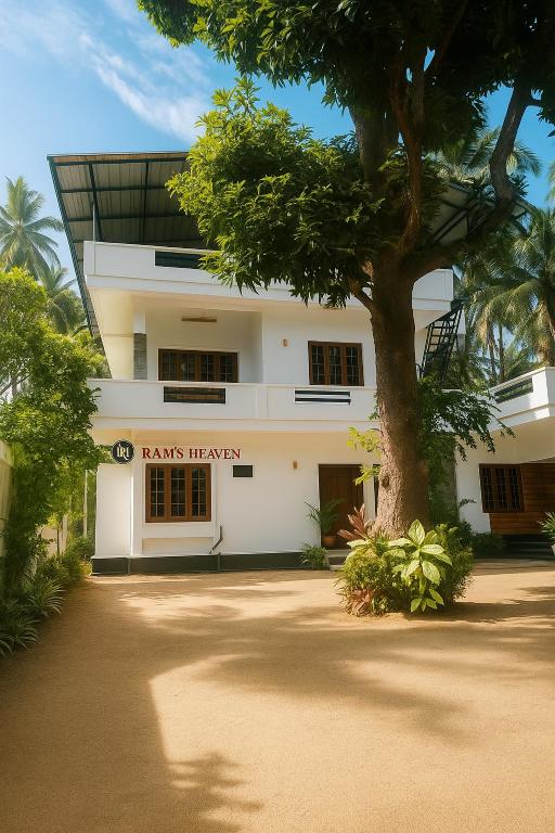 a white building with a tree in front of it at Ram's Heaven in Guruvāyūr