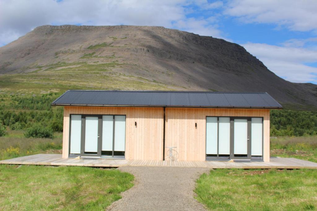 a small building in front of a mountain at Systrakot - Studio Apartments in Talknafjordur