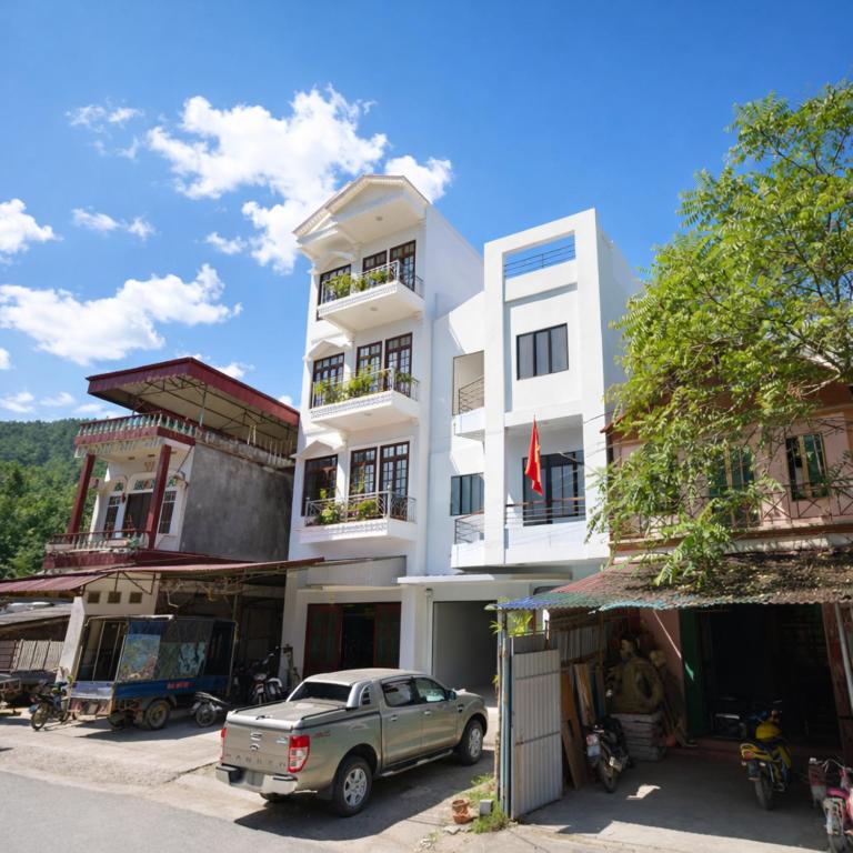 a white building with a car parked in front of it at Thuỳ Dương Hotel Cao Bằng in Bảo Lạc